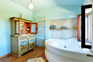 A bathroom with a white bathtub, a wooden cabinet with a mirror, and a tiled wall. - Elegant Villa in Montecosaro Italy with Hot Tub (Montecosaro)