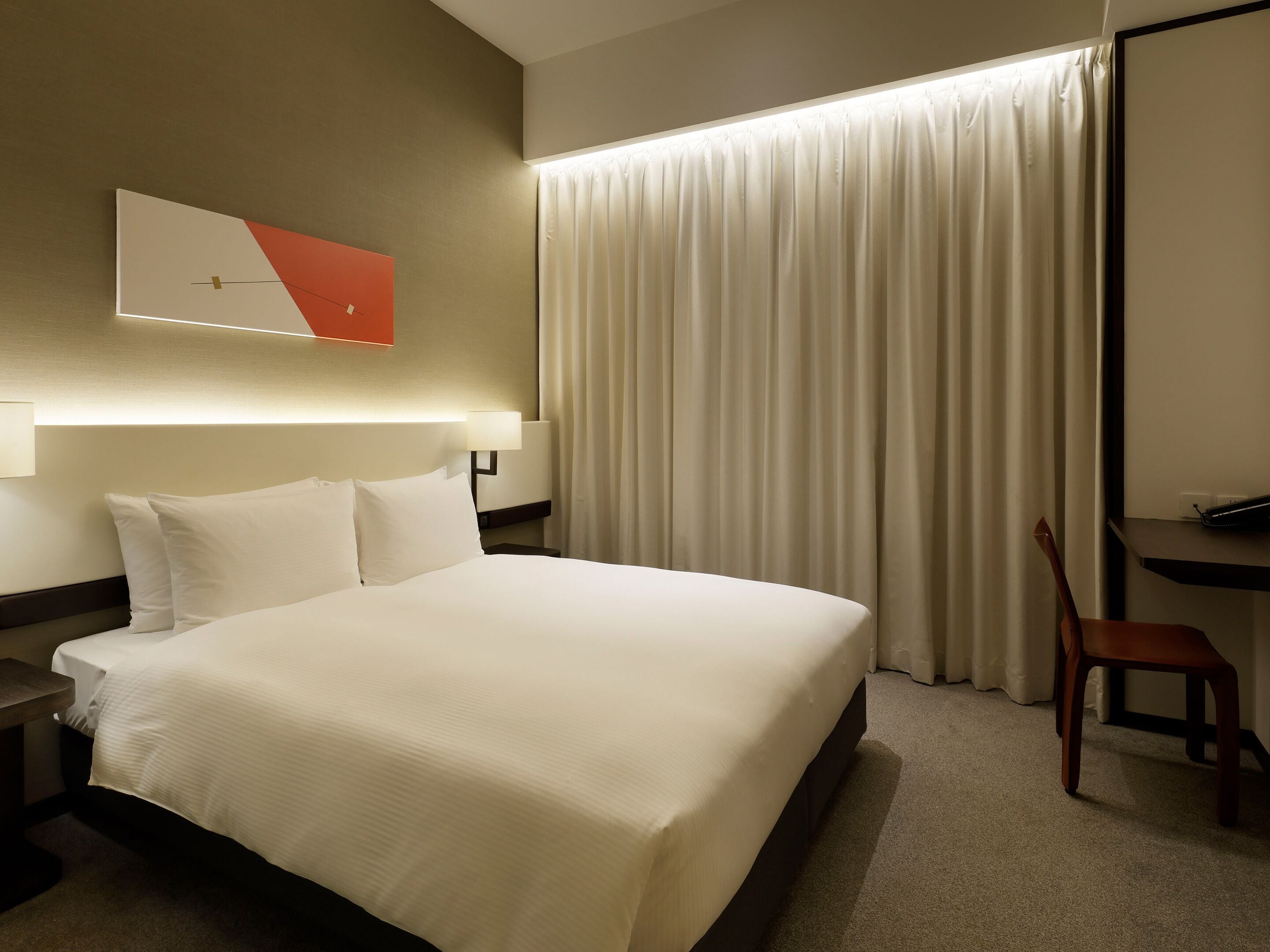 Una habitación de hotel con una cama grande, un escritorio y una silla.