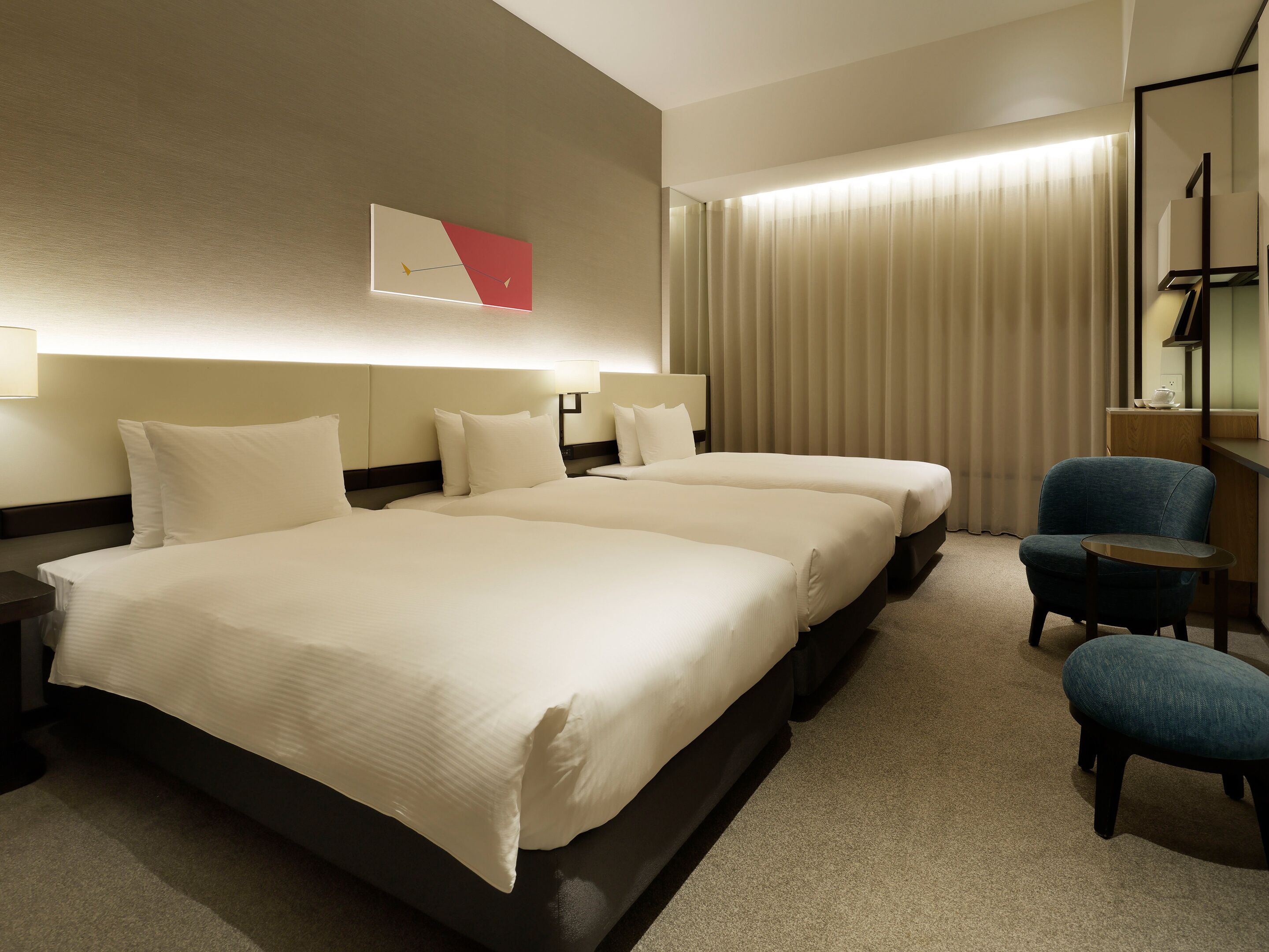A hotel room with a large bed, two bedside tables, a chair, and a wall-mounted clock.