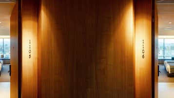A hotel room with a city view, a bed, a desk, and a large wooden door with room numbers.