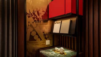 A room with a wooden panel wall, a red cabinet, a marble table with a teapot, cups, and a tray.