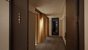 A hallway with a wooden door labeled "1507", a carpeted floor, and a modern ceiling design.