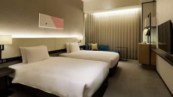 A hotel room with two beds, a desk, a chair, a TV, and a window with curtains.