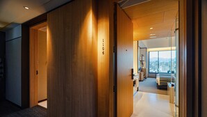Un pasillo de hotel con paredes de madera, un número de habitación visible '1106', y una vista parcial de un dormitorio con cama y vista a la ciudad.