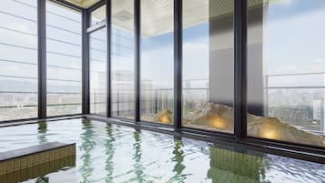 A modern indoor swimming pool with large windows and a city view.