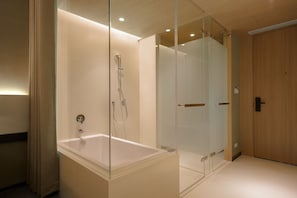 Un baño moderno con ducha de vidrio, una bañera independiente y una puerta de madera.