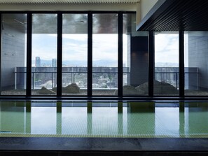 Una piscina interior moderna con amplios ventanales que ofrecen vistas a la ciudad.