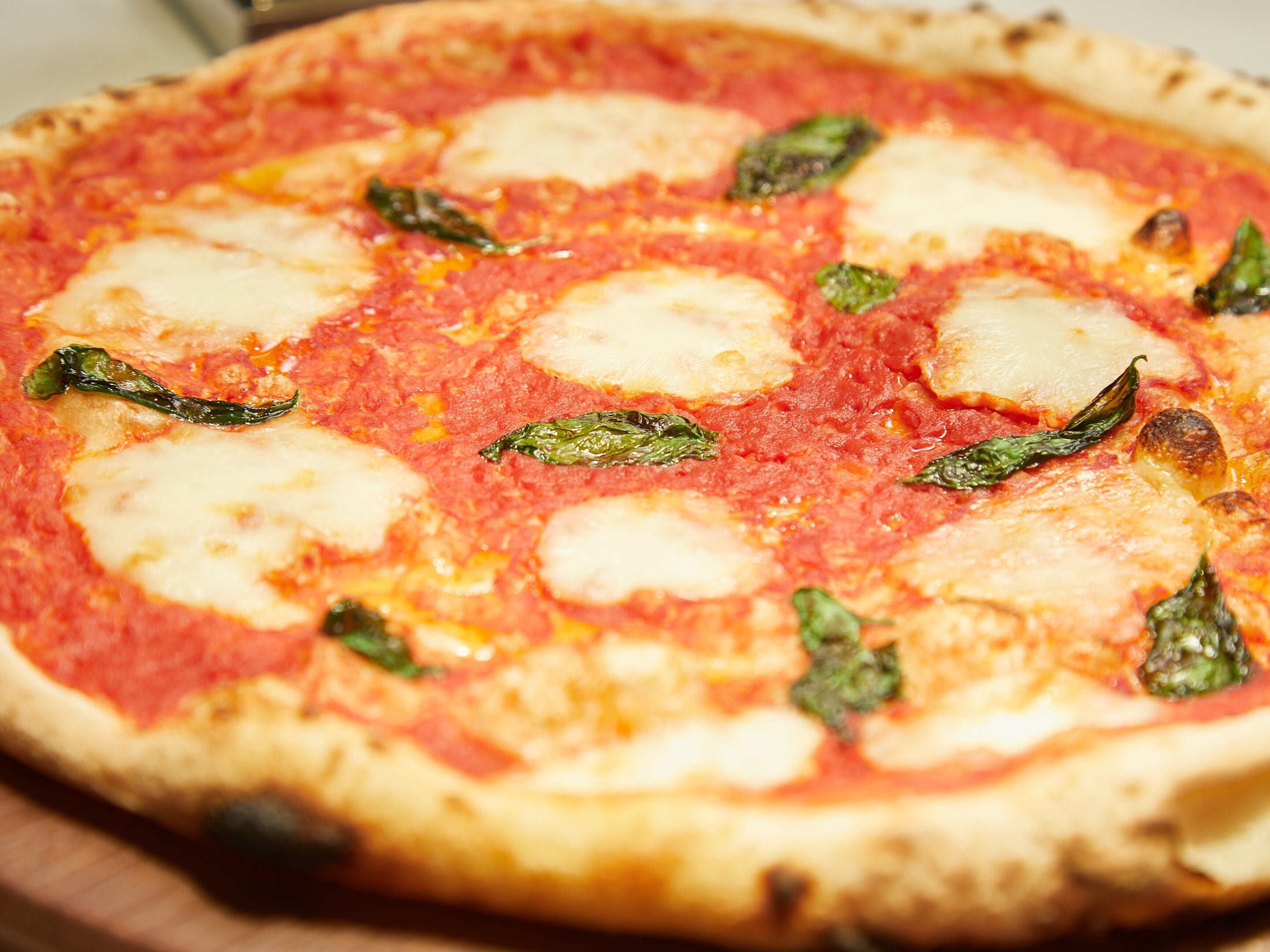A pizza with cheese and basil on a wooden board.