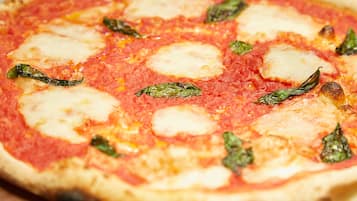 A pizza with cheese and basil on a wooden board.