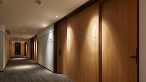 A hotel hallway with wooden doors, carpeted flooring, and recessed lighting.