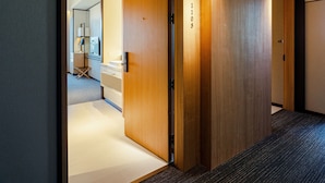 A hallway with wooden doors, a carpeted floor, and a glimpse of a bathroom with a mirror and sink.