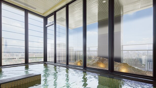 Piscina interior moderna con amplios ventanales que ofrecen vistas a la ciudad.