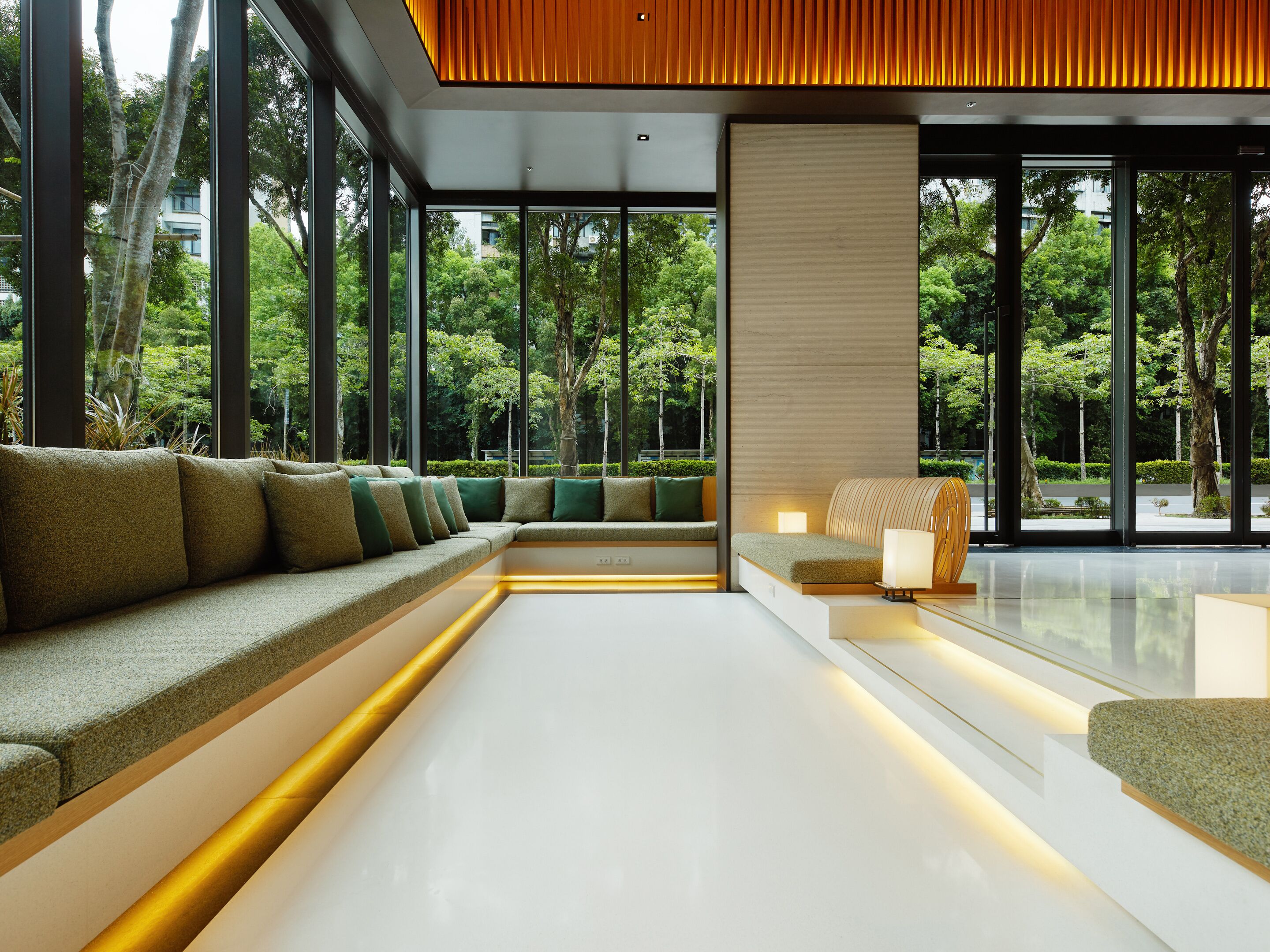 A modern interior with a long white bench, a sofa with cushions, and a wooden accent wall.