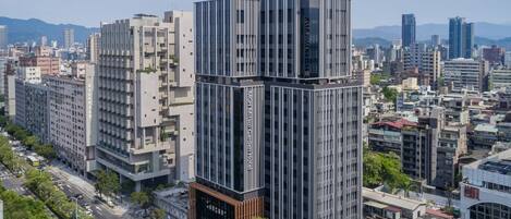 A modern hotel with a unique stacked design, surrounded by a cityscape.