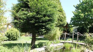 Un giardino tranquillo con uno stagno, un ponticello di legno e una vegetazione rigogliosa.