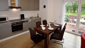 A modern kitchen with a dining area, a coffee maker, and a clock on the wall. - Villa am Meer in Boiensdorf mit Terrasse (Boiensdorf)