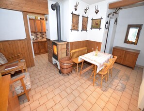 Una stanza accogliente con un camino a legna, un tavolo da pranzo con sedie, un cesto in vimini e pensili in legno.