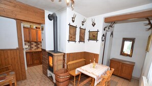 Un coin repas chaleureux avec une table et des chaises, une cheminée et des bois de cerf accrochés au mur.