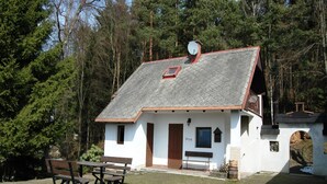 Un petit bâtiment blanc avec un toit en pente, une antenne parabolique et une table de pique-nique avec des bancs.