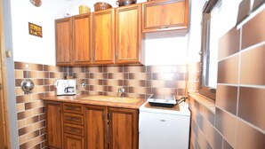 Une cuisine compacte avec des meubles en bois, un réfrigérateur blanc et un pare-feu en carrelage.