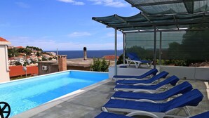 A rooftop pool with blue lounge chairs and a view of the sea. - Holiday Home in Korcula With Sea View (Korčula)