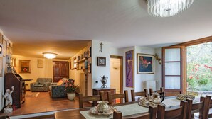 Ein Essbereich mit einem Holztisch, gedeckt für sechs Personen, umgeben von Holzstühlen mit gewebten Sitzflächen. Im Hintergrund steht ein Klavier, und der Raum strahlt eine warme, einladende Atmosphäre aus, die durch gerahmte Kunstwerke an den Wänden ergänzt wird.