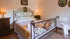 Ein Schlafzimmer mit einem Metallbett, zwei Nachttischen mit Lampen, einem Holzbeistelltisch und einem weißen Stuhl.