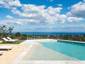 A swimming pool with a clear view of the ocean and a distant cityscape. - Belvilla by OYO La Torretta Dieci (Zafferana Etnea)