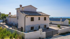 A two-story building with a tiled roof, a small tower-like structure on the roof, and a paved courtyard with a fence. - Modern Villa With Private Pool Near Labin and the Beach (Rasa)