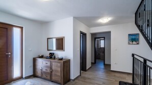 A hallway with wooden flooring, a dark wooden cabinet with drawers, a mirror, and a painting on the wall. - Modern Villa With Private Pool Near Labin and the Beach (Rasa)