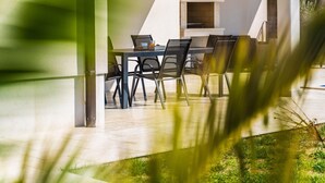An outdoor dining area with a table and chairs, a built-in grill, and a view of the surrounding greenery. - Modern Villa With Private Pool Near Labin and the Beach (Rasa)
