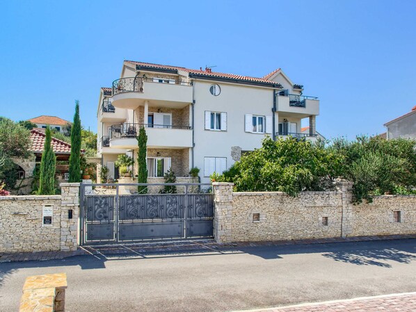 A multi-story residential building with a stone facade, balconies, and a gated entrance. - Modish Apartment in Murter with Hot Tub (Murter-Kornati)