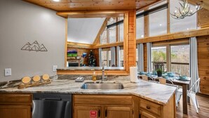 Une cuisine dotée de meubles en bois, d’un lave-vaisselle, d’un évier et d’un coin repas avec une table et des chaises.