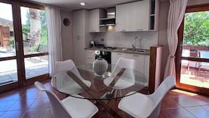 A modern kitchen with white cabinets, a glass dining table, and white chairs. - Charming Holiday Home Near Sea (Castellammare del Golfo)