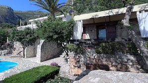 A stone-walled building with a pool, surrounded by greenery and mountains. - Charming Holiday Home Near Sea (Castellammare del Golfo)