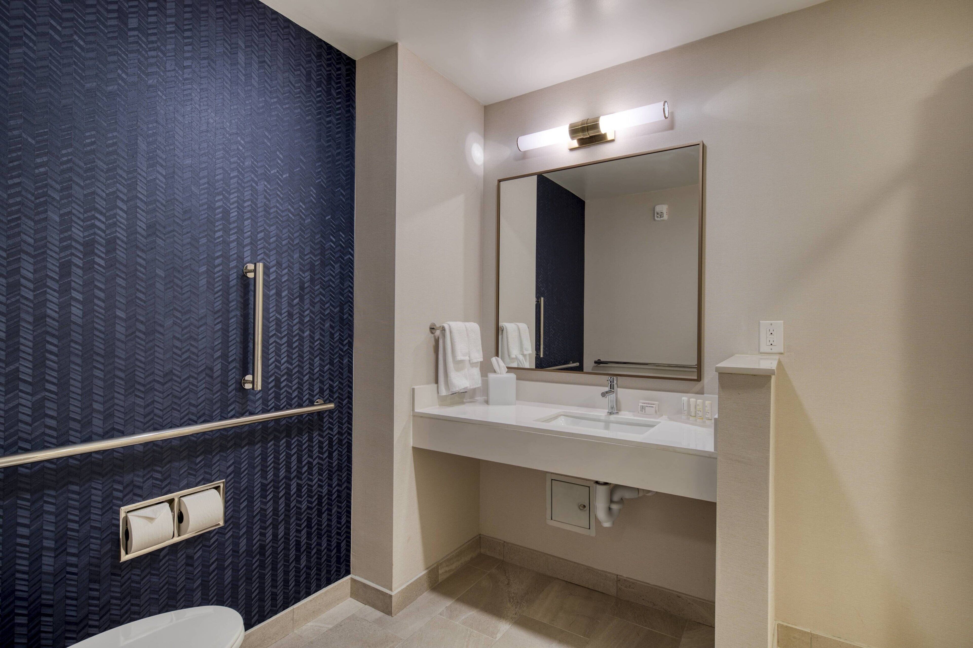 Une salle de bain moderne avec un grand miroir, deux lavabos et des toilettes.