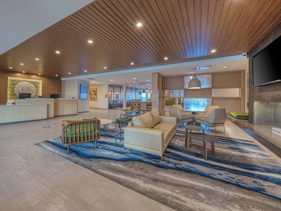 A spacious lobby with a reception desk, seating area, and a large flat-screen TV mounted on the wall.