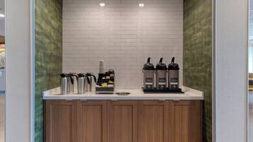 Angolo caffè con due macchine da caffè, un erogatore e diverse tazze termiche.
