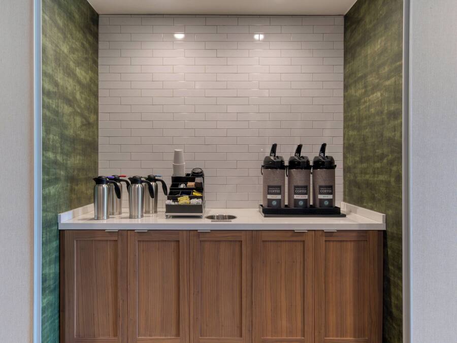 Angolo caffè con due macchine da caffè, un erogatore e diverse tazze termiche.