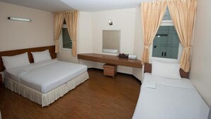 Une chambre d’hôtel avec deux lits simples, un bureau en bois, un miroir et une fenêtre avec des rideaux.