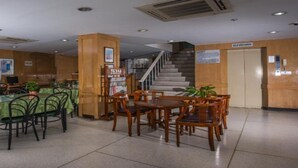 Un hall d’entrée avec un escalier, des murs en bois, un comptoir d’accueil et un espace repas avec des tables et des chaises.