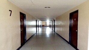 Un long couloir étroit, avec des portes de part et d’autre, un sol carrelé et le chiffre « 7 » peint sur le mur de gauche.