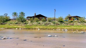 Une maison avec une grande cheminée, un petit porche et une vue sur une rivière.
