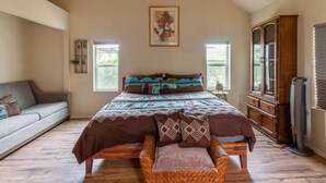 Une chambre à coucher avec un grand lit, un canapé, une armoire en bois et un téléviseur.