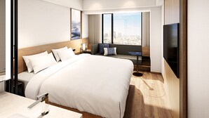 Quarto de hotel moderno com uma cama grande, televisão, área de estar e vista para a cidade.
