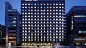 Um hotel de vários andares com fachada moderna, janelas iluminadas e sinalização com 'Fairfield by Marriott'.