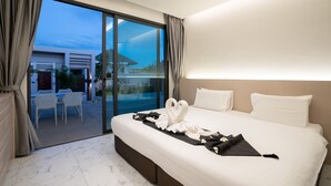 Ein Hotelzimmer mit einem großen Bett, Blick durch eine Schiebetür in einen Außenbereich und einer gut beleuchteten Decke.