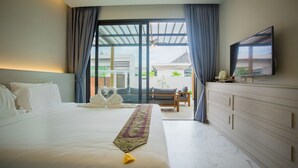 Ein Hotelzimmer mit einem großen Bett, einem Flachbildfernseher, einer Couch und Blick ins Freie.