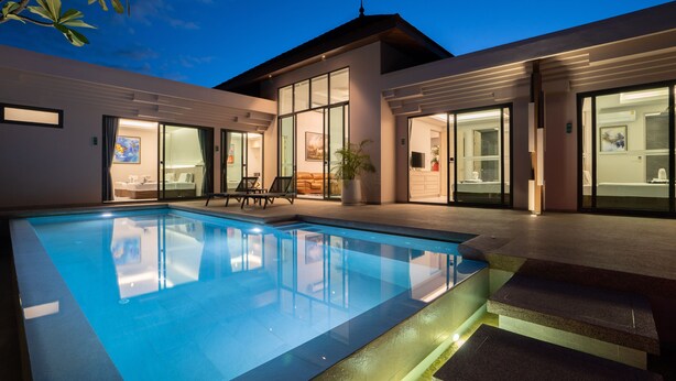 Ein modernes Haus mit Pool, großen Glasfenstern und einem gut beleuchteten Innenraum.