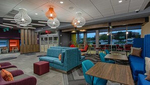 A modern lounge area with seating and tables, large windows, and decorative lighting. - Tru by Hilton Columbus Airport (Columbus)